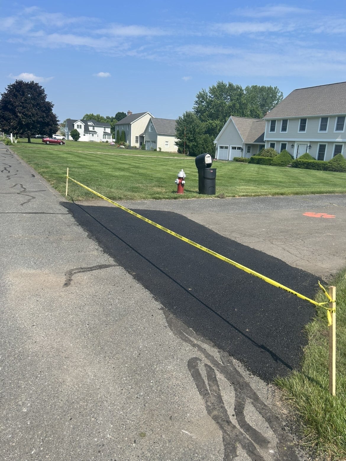 Fresh asphalt patch along a neighborhood road