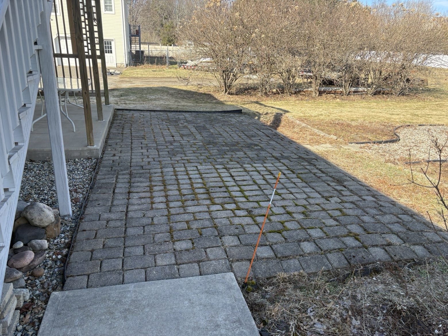 Before: old paver patio beside a porch