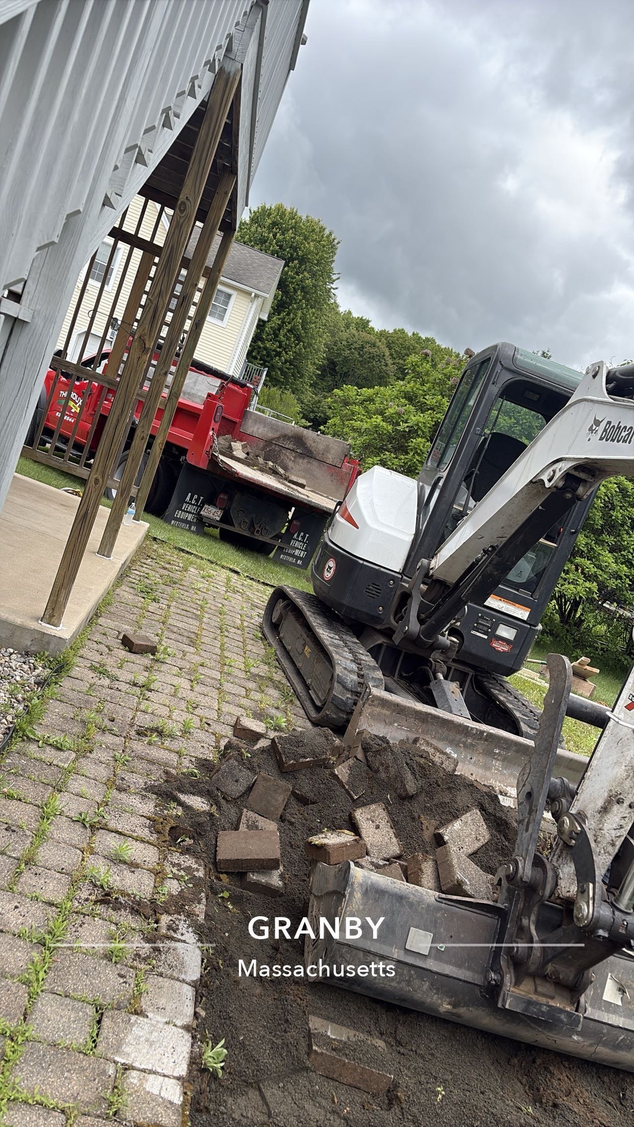 Bobcat removing old pavers during a patio conversion